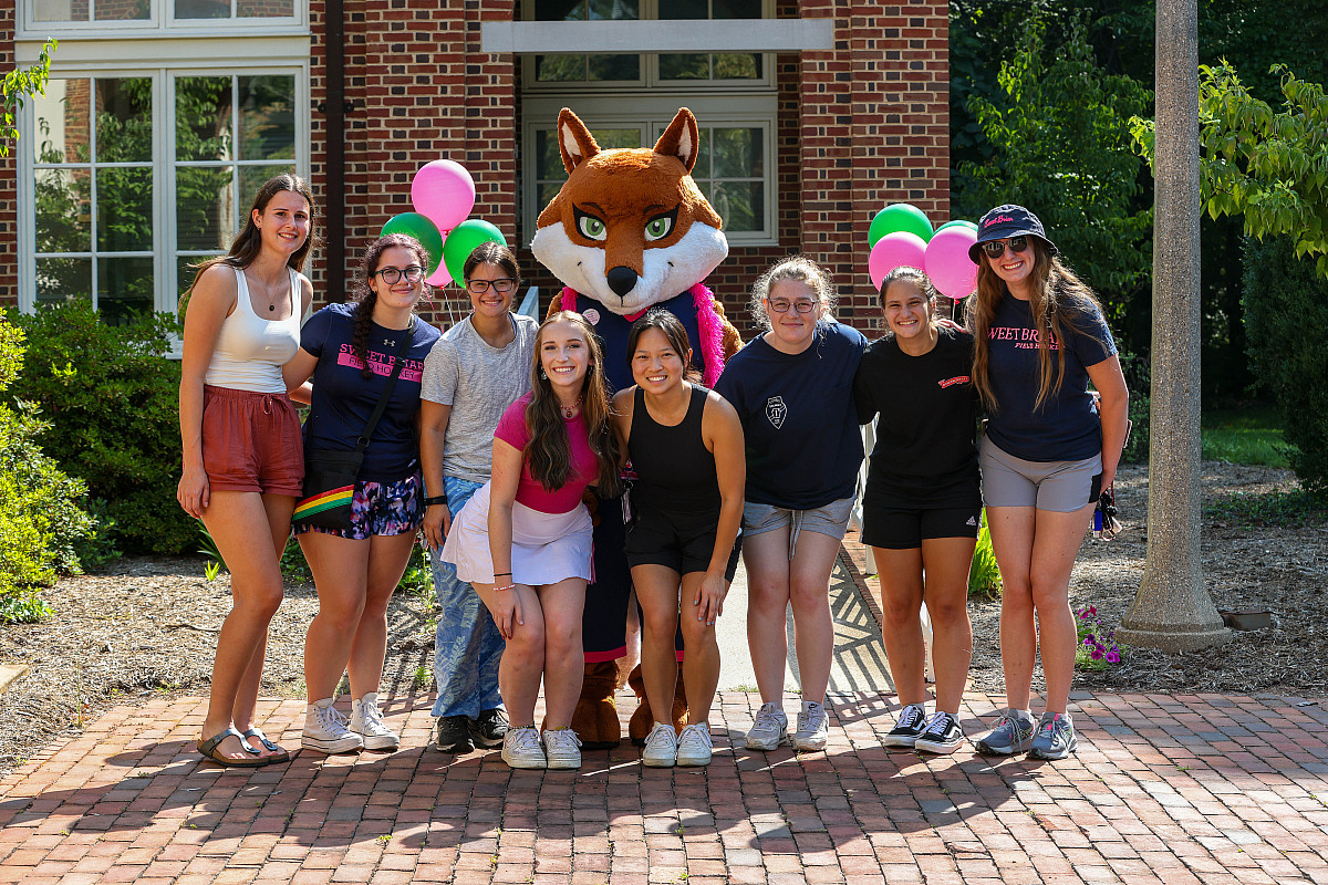 Students post for a photo with mascot
